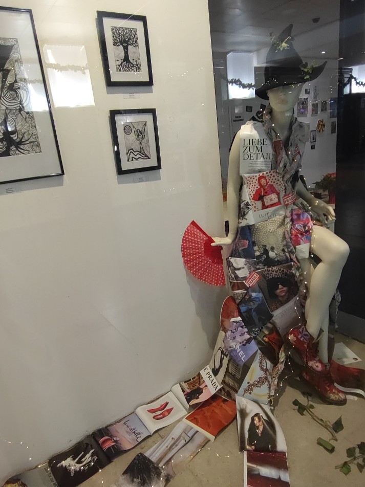 A collage fashion witch mannequin displayed in an exhibition space, wearing a black witch hat and collage costume.